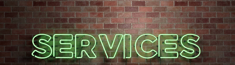 image of brick wall with "services" neon sign